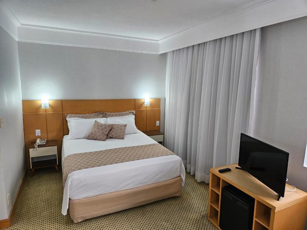a hotel room with a bed and a flat screen tv at Flat Hotel Slaviero Guarulhos in Guarulhos