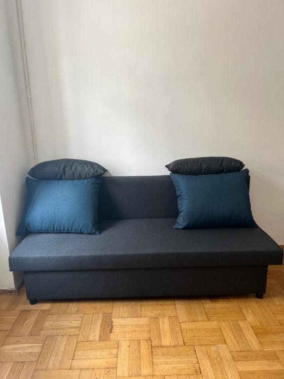 niebieska kanapa z dwoma poduszkami na drewnianej podłodze w obiekcie 8-9Sam Apartment vienna w Wiedniu