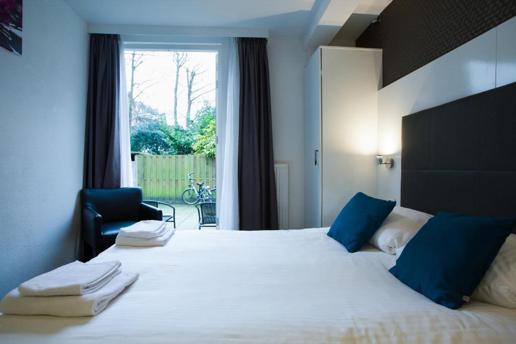 a bedroom with a large white bed with blue pillows at Hotel Vossius Vondelpark in Amsterdam