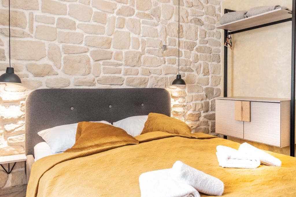 a bedroom with a large bed with a stone wall at L&B amphitheater apartments in Pula