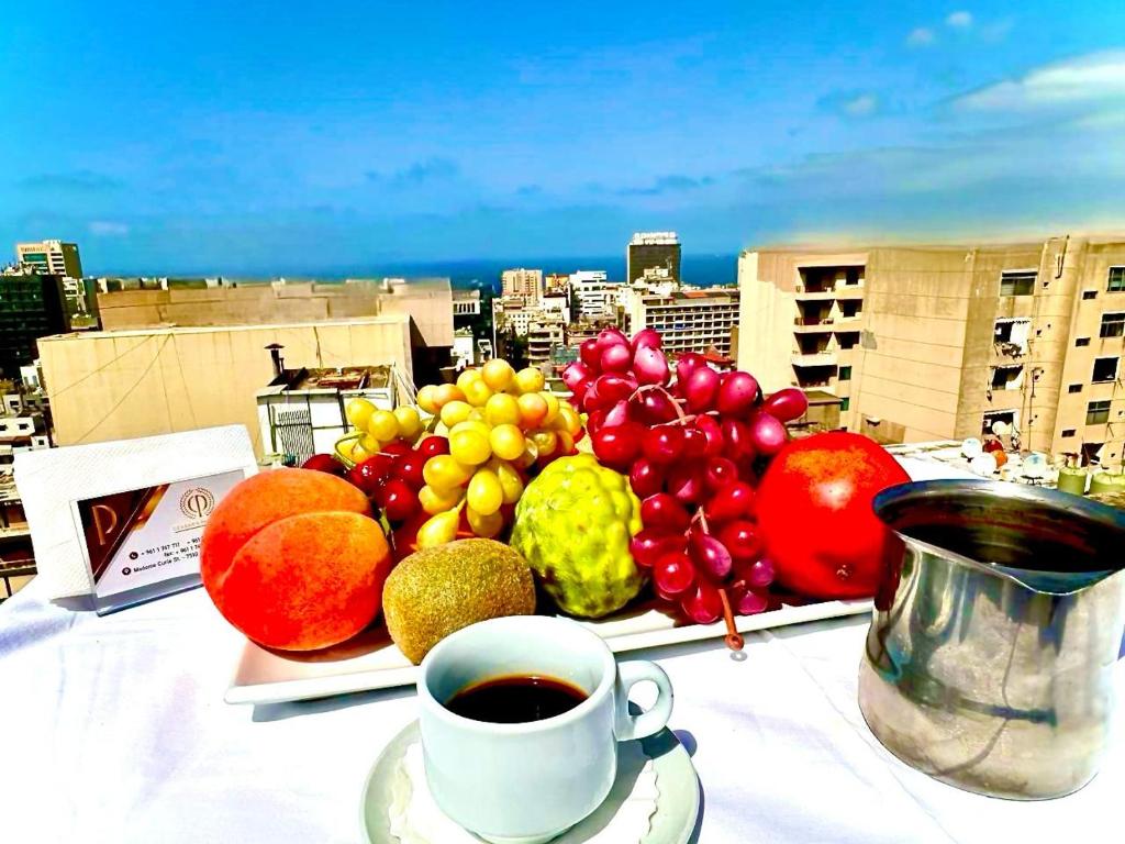 a plate of fruit on a table with a cup of coffee at Caesar's Park Hotel in Beirut