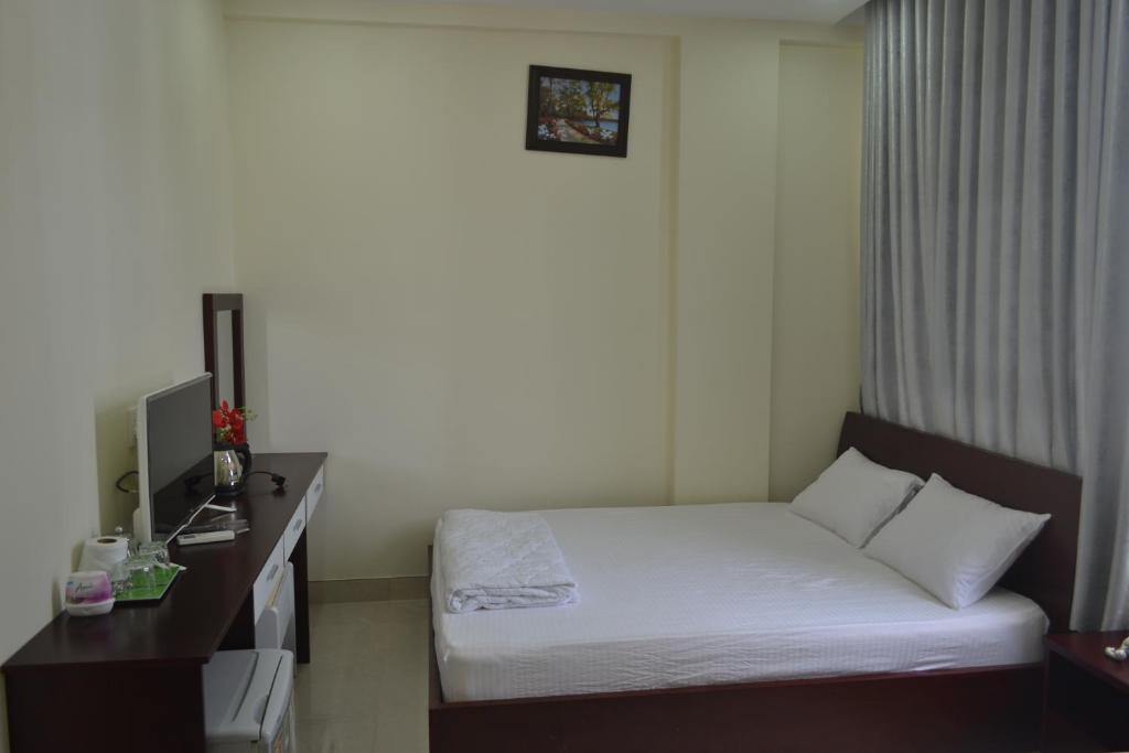 a hotel room with a bed and a desk and a monitor at Khách sạn Minh Nhân in Vung Tau