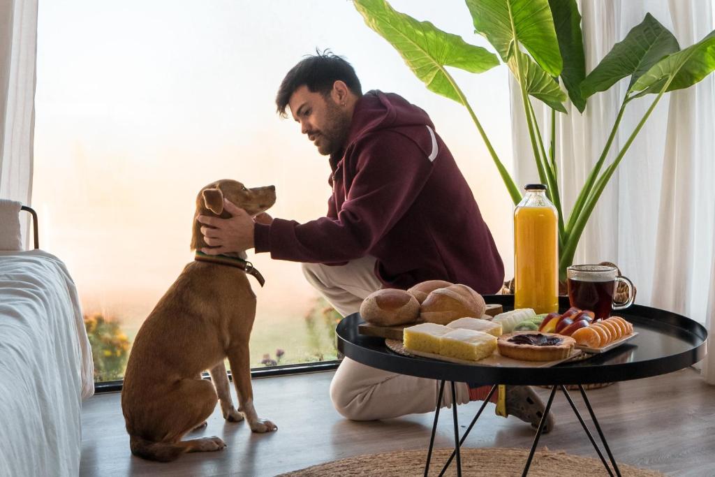 a man playing with a dog next to a table with food at Paso Calmo Cabañas in Villa General Belgrano