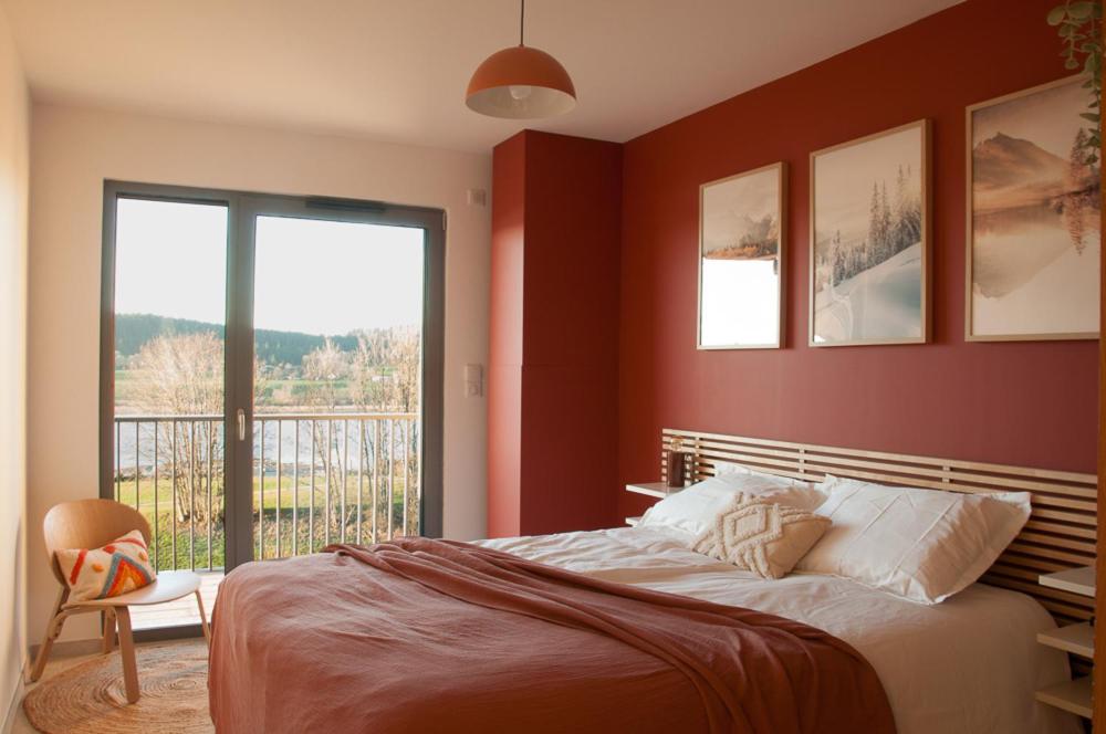 Schlafzimmer mit roten Wänden, einem Bett und einem Fenster in der Unterkunft Duplex 6 personnes, vue panoramique sur lac in Malbuisson