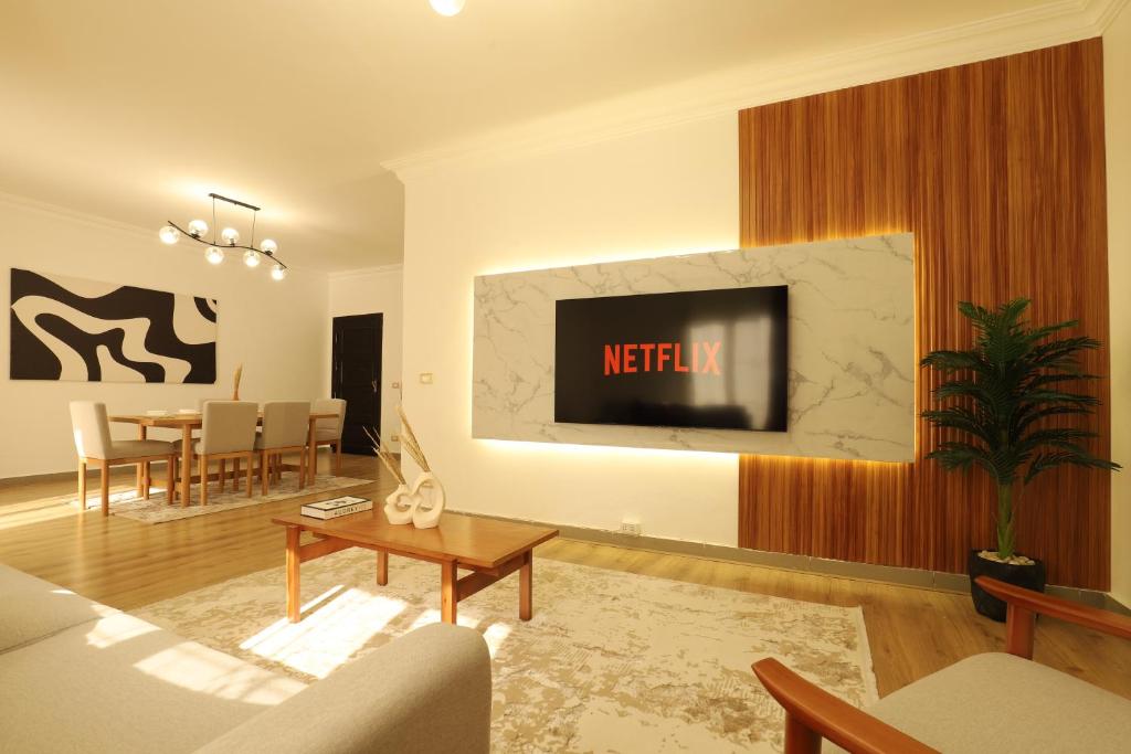 a living room with a tv on a wall at Signature Stays: Modern Chic Apt in Cairo