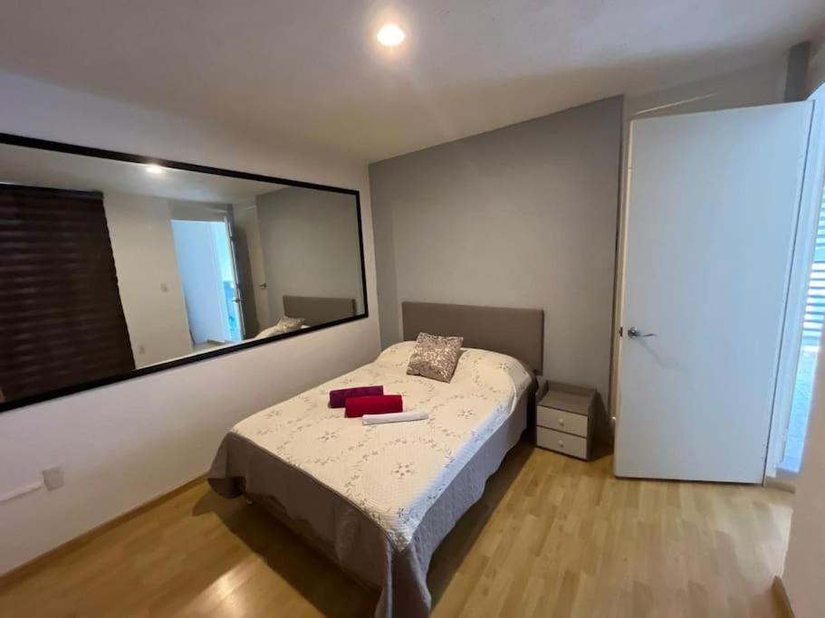 1 dormitorio con cama y espejo grande en Oaxaca departamento azul, en Oaxaca City