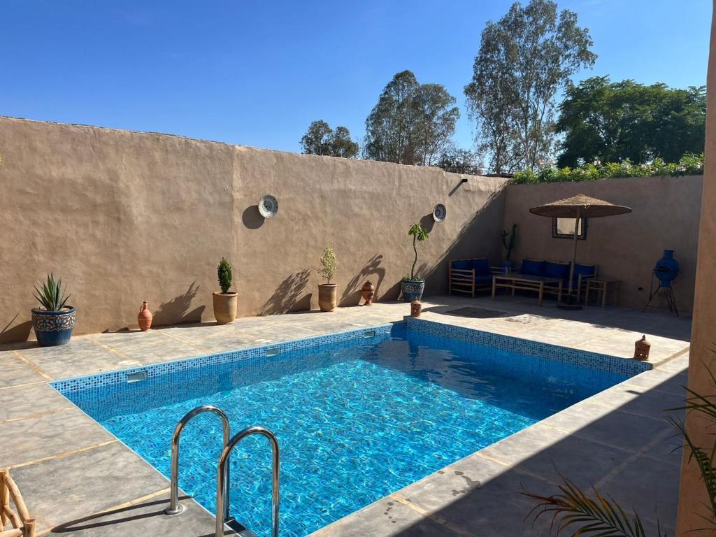 a swimming pool next to a concrete wall at Villa C à 5km du centre in Marrakech