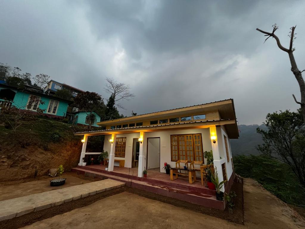 een klein huis op een heuvel met een hemel bij Orange Bari Farmstay in Darjeeling