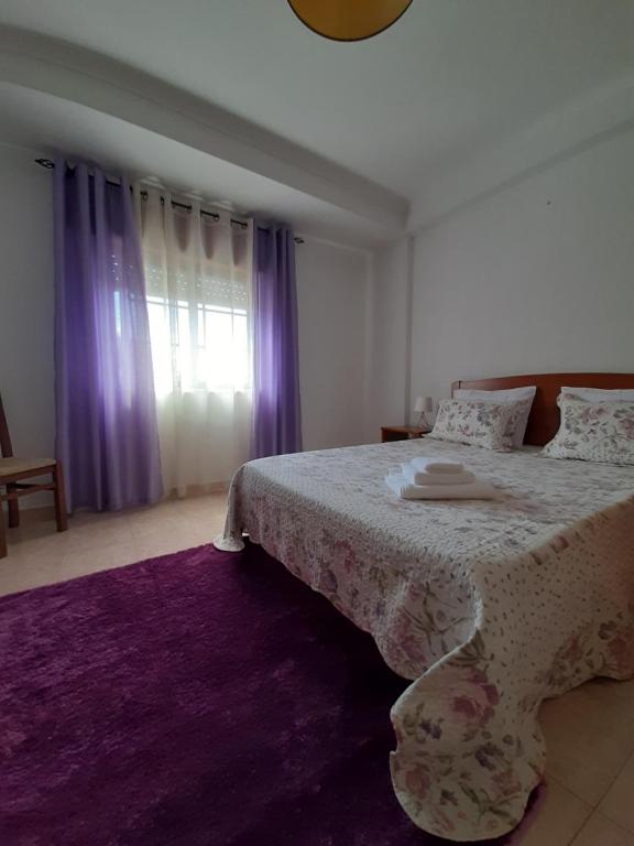 una camera con un grande letto e un tappeto viola di Lugar do Sonho Apartamento a Cercal
