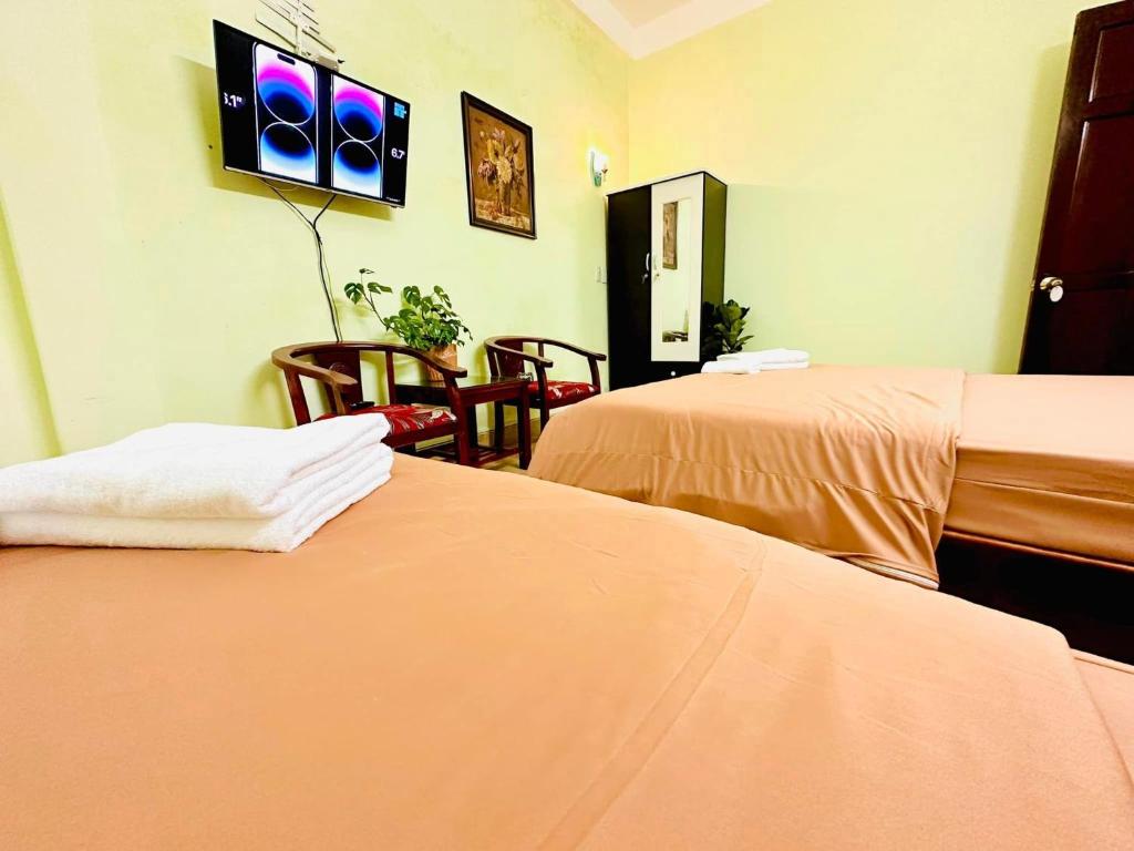 a room with two beds and a tv on the wall at GUEST HOUSE PHÚ XUÂN in Thôn Lại Thê