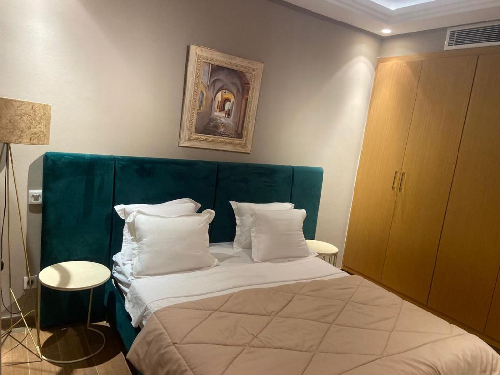 een slaapkamer met een bed met een groen hoofdeinde en witte kussens bij Appartement en résidence tunis in Tunis
