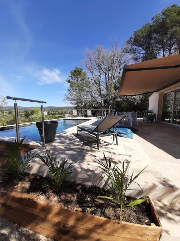 un patio avec un banc et une piscine dans l'établissement Maison au pied de la st victoire avec piscine, à Pourrières