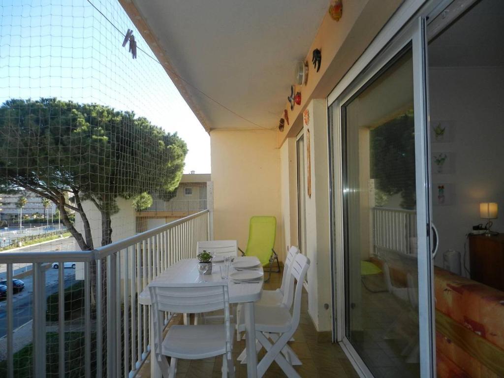 d'une petite table et de chaises blanches sur un balcon. dans l'établissement Appartement 2 pièces cabine avec piscine, tennis, proche plage et marché - 4 couchages, Le Lavandou - FR-1-251-802, au Lavandou