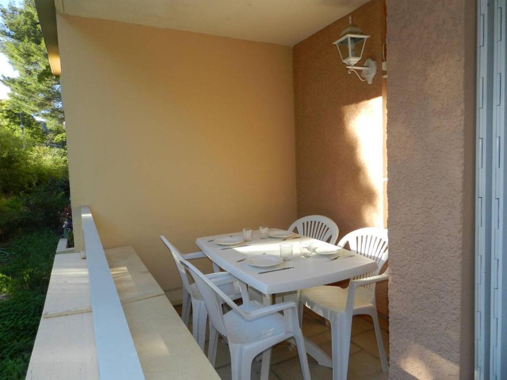 une table blanche et des chaises sur une terrasse dans l'établissement Appartement 2 Pièces avec Parking à 2 Pas de la Plage - Bormes-les-Mimosas - FR-1-251-810, à Bormes-les-Mimosas