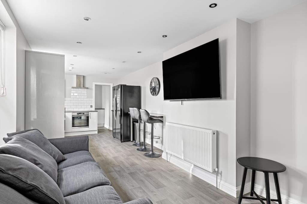 a living room with a couch and a tv on the wall at Brand New 5 Bedroom House in Plymouth