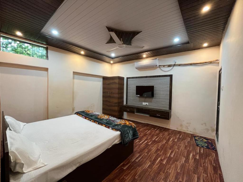 Hotel Varanasi Paradise - Best Seller - Parking facilities في فاراناسي: غرفة نوم بسرير وتلفزيون بشاشة مسطحة