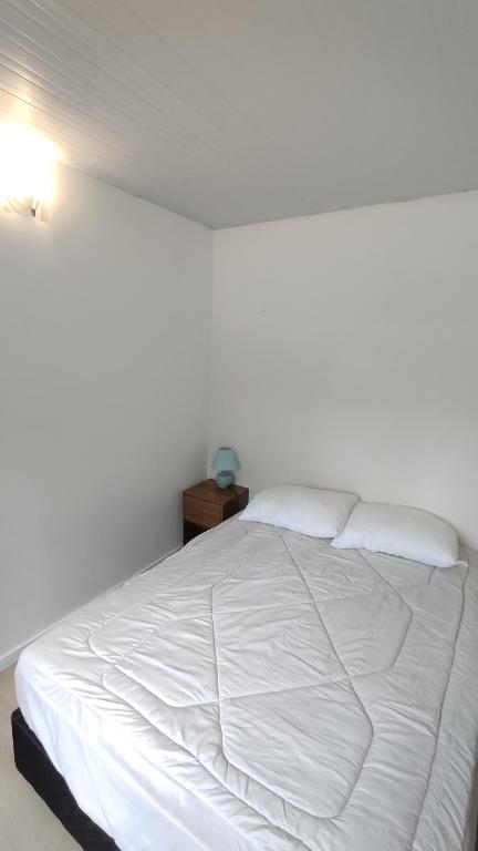 a white bed in a bedroom with a night stand at Tiny house, casa de playa océan park in Ocean Park