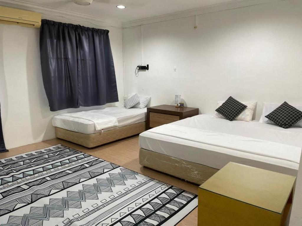 1 dormitorio con 2 camas, mesa y ventana en #KangaQHomestay99 en Kangar