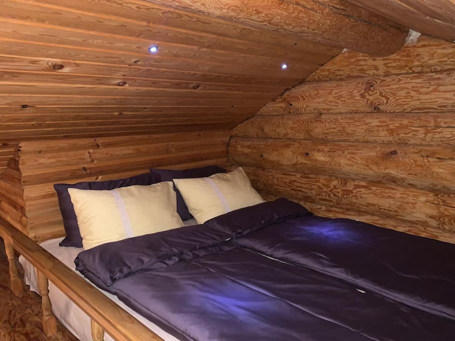 Ce lit se trouve dans un chalet doté de murs en bois. dans l'établissement Russet & Rowanberry - Russet Holiday House, à Paide