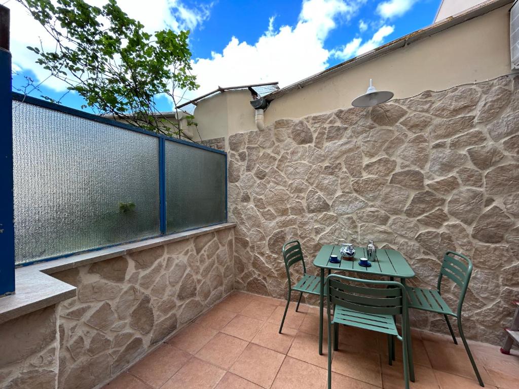 patio ze stołem i krzesłami na kamiennej ścianie w obiekcie Appartamento Firenze Mayer we Florencji