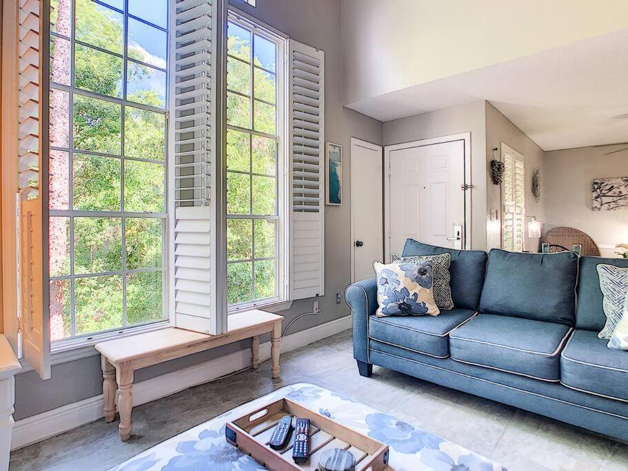 ein Wohnzimmer mit einem blauen Sofa und Fenstern in der Unterkunft Disney 15 min Stunning Enchanted Lake House in Kissimmee