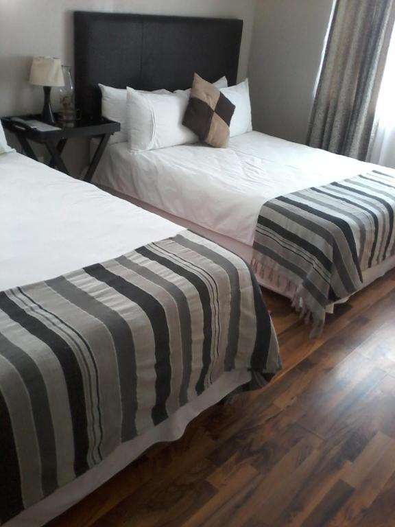 two beds sitting next to each other in a room at Palm Springs B and B and Self Catering in Butterworth
