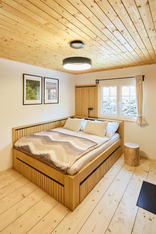 a bed in a room with a wooden ceiling at Romantika v Jeseníkách - Privátní chata Dori s finskou saunou v ceně in Kouty