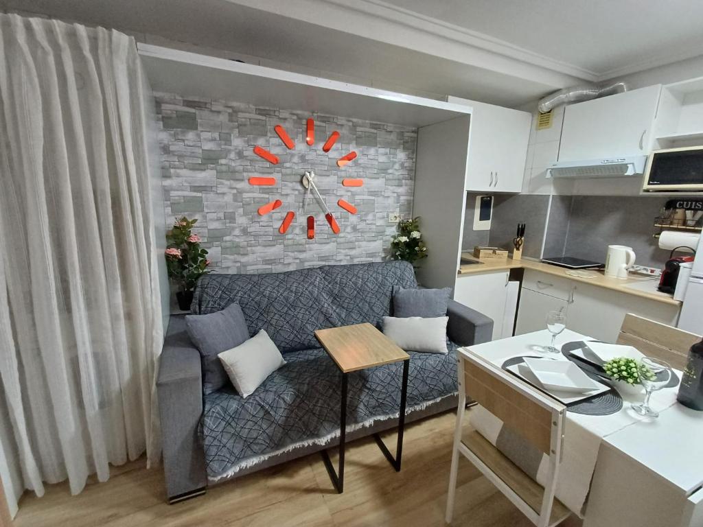 a living room with a couch and a clock on a wall at Alicante Denia Apartments in Alicante
