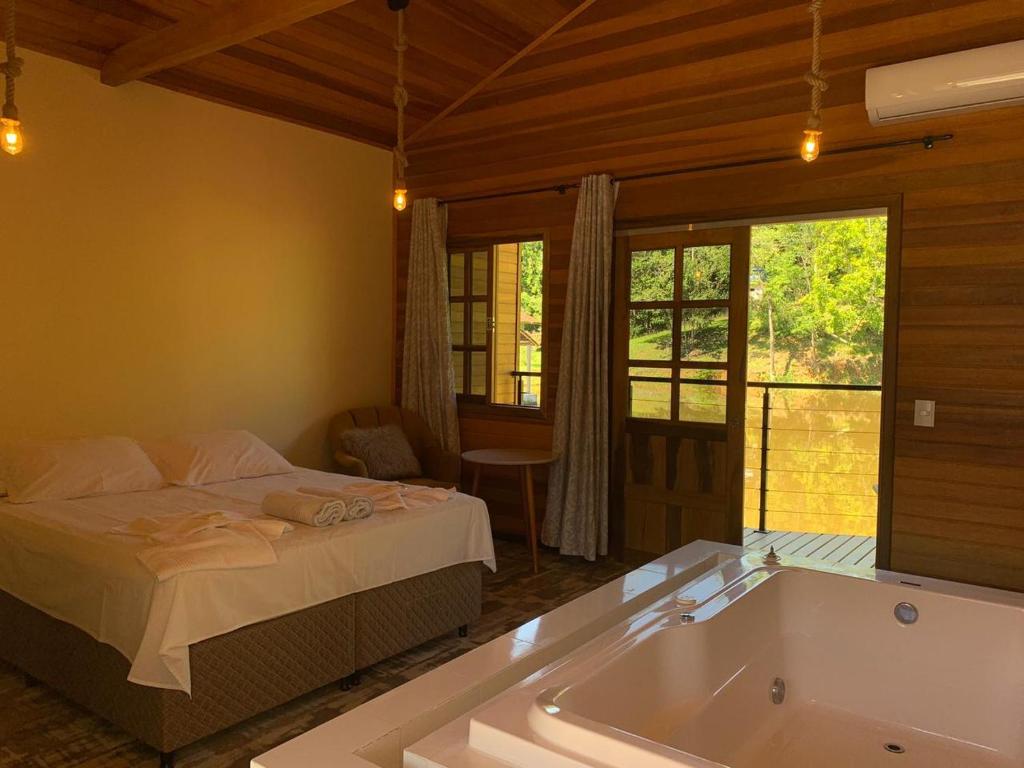 Pousada Recanto Pomerano في بوميرودي: غرفة نوم مع سرير وحوض استحمام