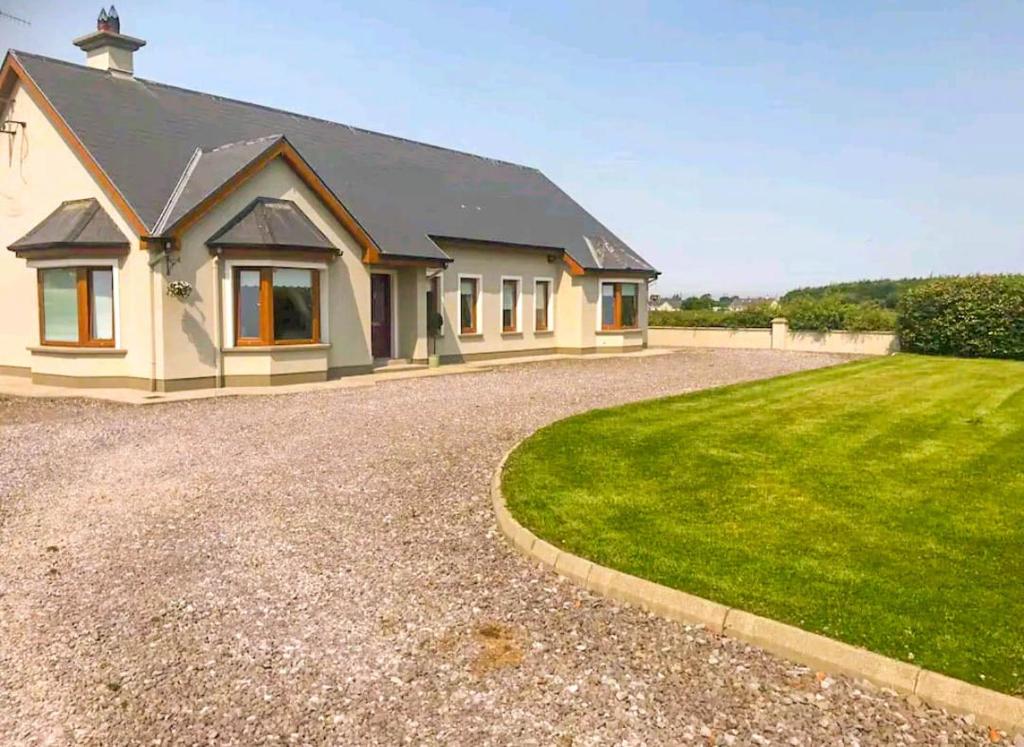 a large white house with a gravel driveway at An Ghlaise Bheag in Kilmore
