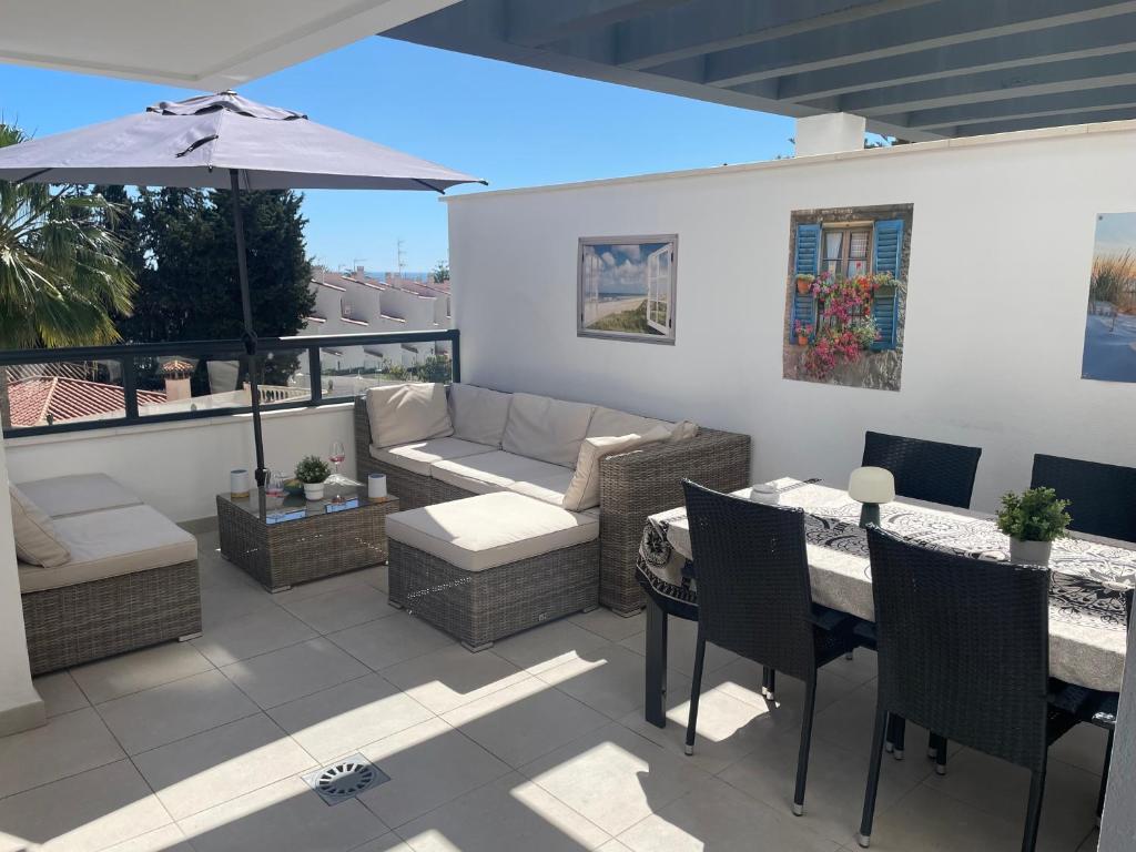 patio z kanapą i stołem z parasolem w obiekcie Casa Torremolinos w mieście Torremolinos