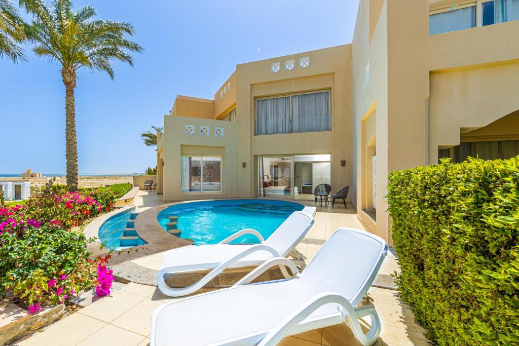 eine Villa mit einem Pool und 2 Liegestühlen in der Unterkunft Sataya Resort Marsa Alam in Marsa Alam City