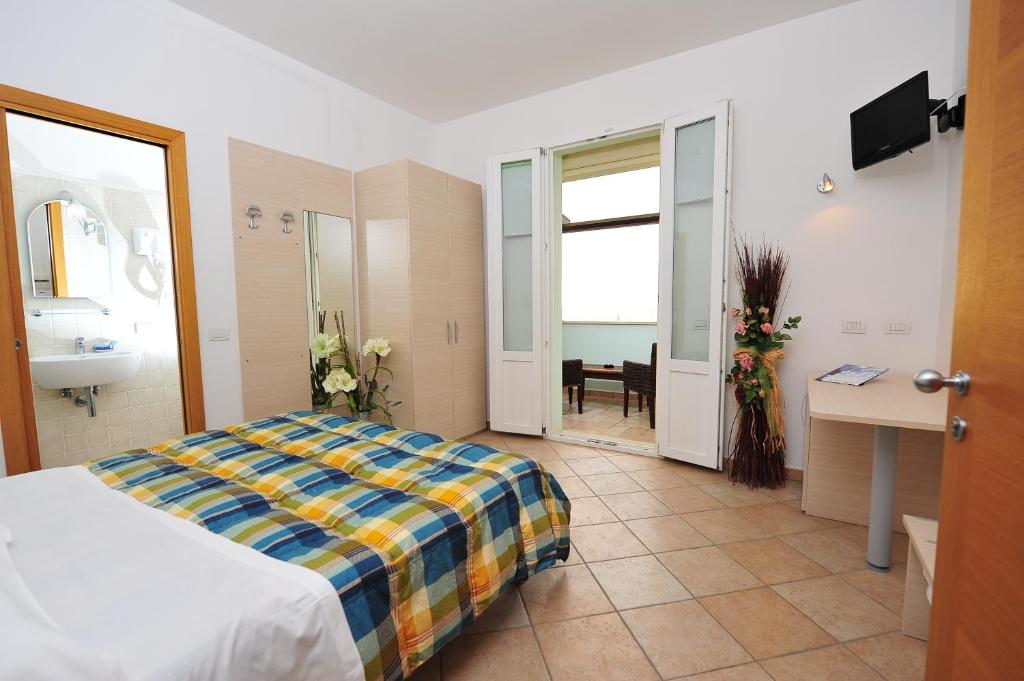 a bedroom with a bed and a bathroom with a sink at Hotel Aurora in San Vincenzo