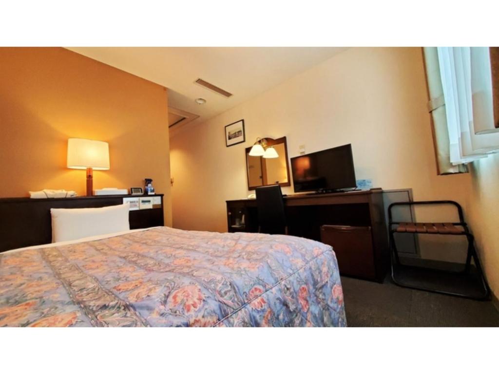 ein Hotelzimmer mit einem Bett, einem Schreibtisch und einem TV in der Unterkunft Nobeoka Urban-Hotel - Vacation STAY 30390v in Nobeoka