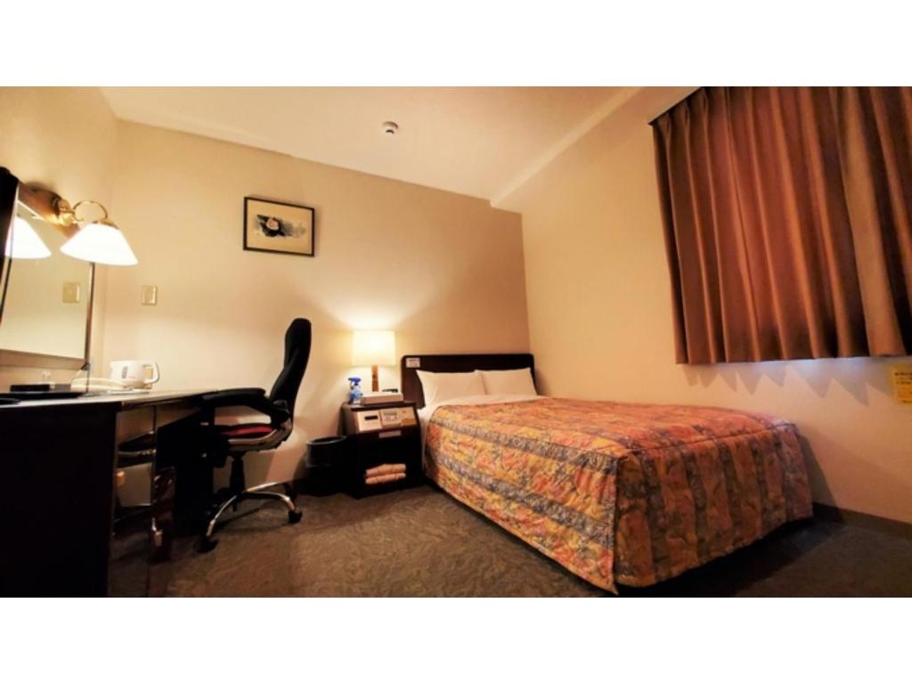 Cette chambre comprend un lit et un bureau. dans l'établissement Nobeoka Urban-Hotel - Vacation STAY 30525v, à Nobeoka