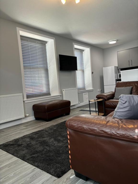 a living room with a leather couch and a tv at Argyle House Wick in Wick