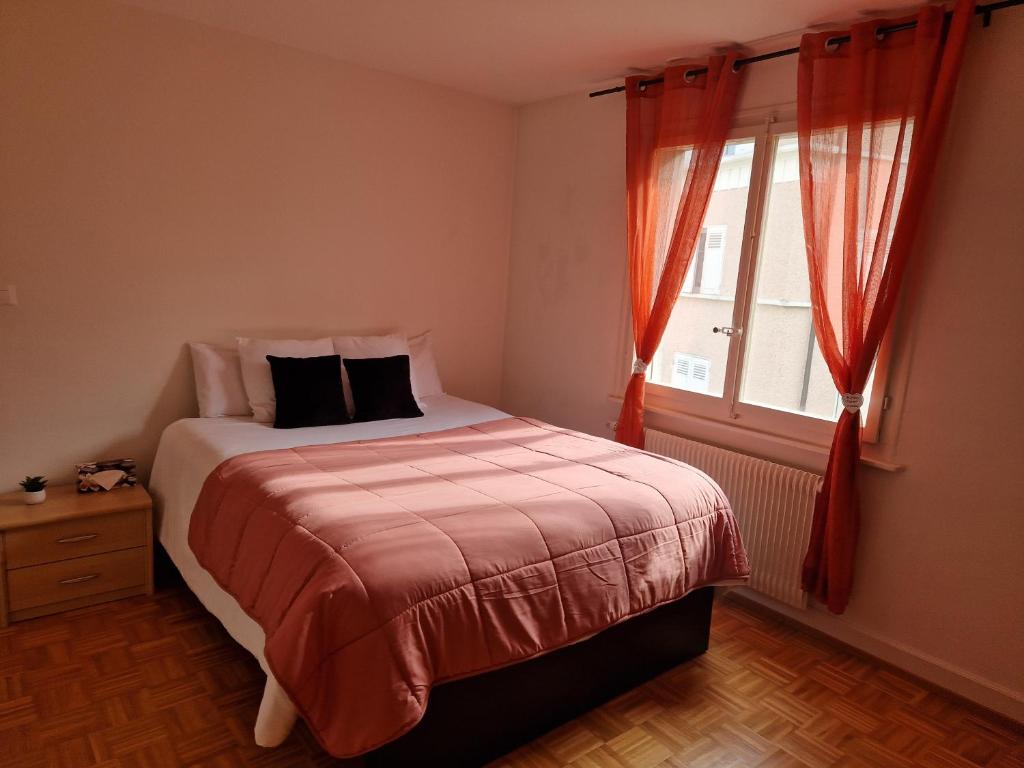 a bedroom with a bed with red curtains and a window at La casa de los viajeros in Vevey
