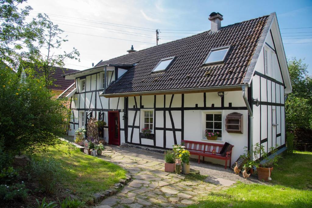 ein weißes und schwarzes Haus mit einer roten Bank in der Unterkunft Haus Nr. 9 in Ruppichteroth