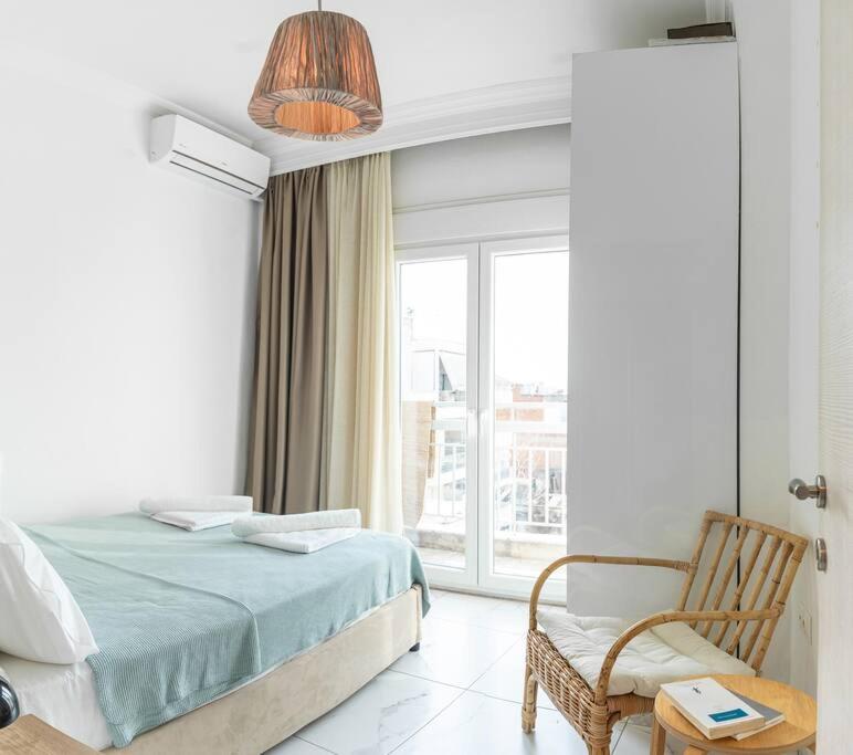 een slaapkamer met een bed, een stoel en een raam bij Queens suite in Thessaloniki