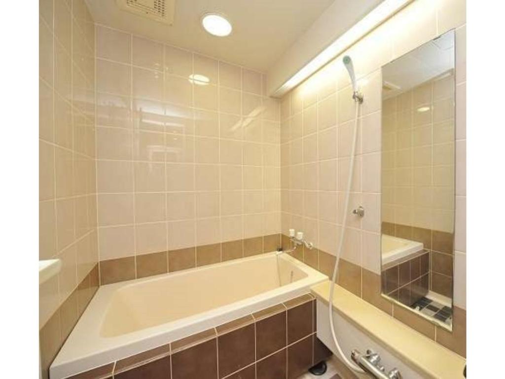 W łazience znajduje się wanna i lustro. w obiekcie Furano Hops Hotel - Vacation STAY 41210v w mieście Kami-furano