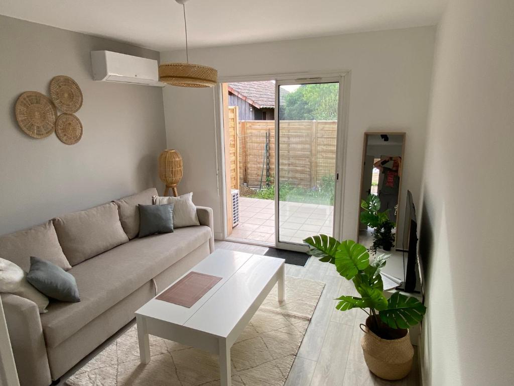 uma sala de estar com um sofá e uma mesa em Appartement à Villenave d'Ornon avec jardin fraîchement rénové em Le Brucat