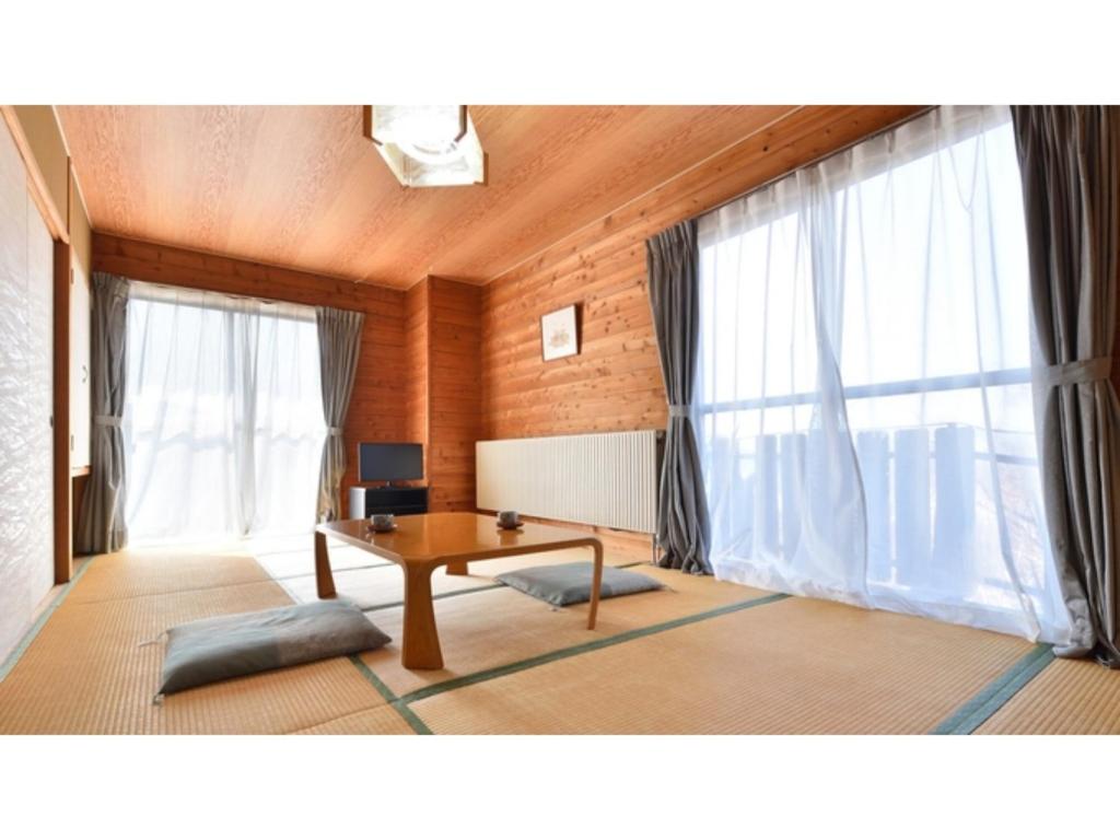 a living room with a table and two windows at Hotel Takimoto - Vacation STAY 43487v in Yamanouchi
