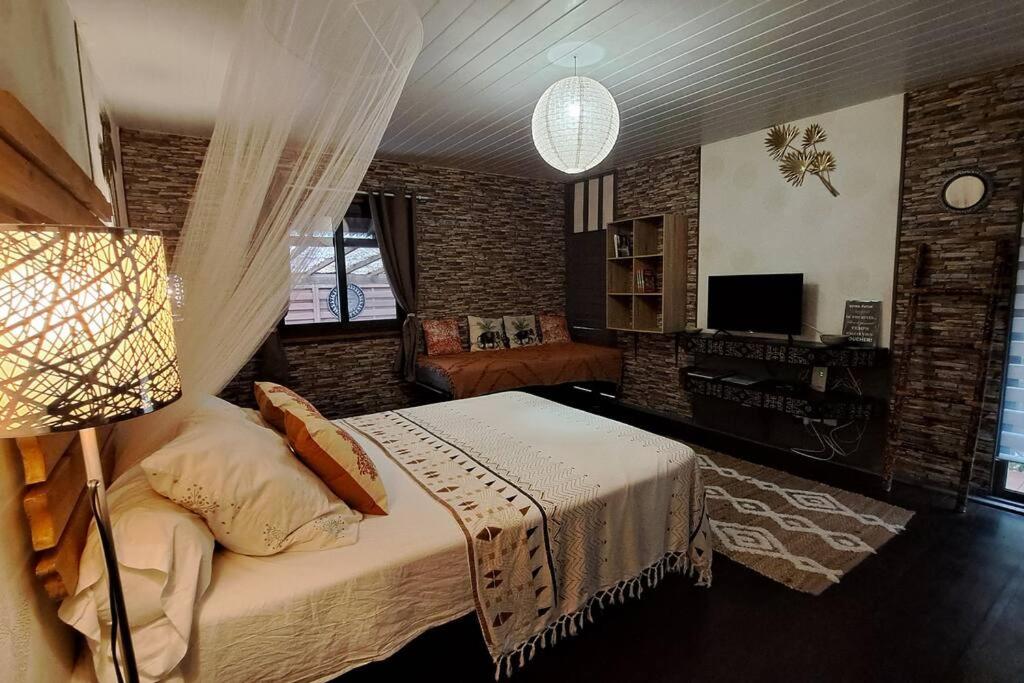 1 dormitorio con cama, sofá y TV en Faaora Lodge, little paradise, en Haapiti