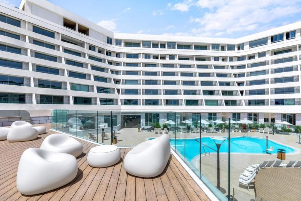 un grande edificio con sedie bianche e una piscina di סוויטות עם נוף צמודות לים במתחם SeaSide היוקרתי עם בריכה - By SEAELO EILAT a Eilat