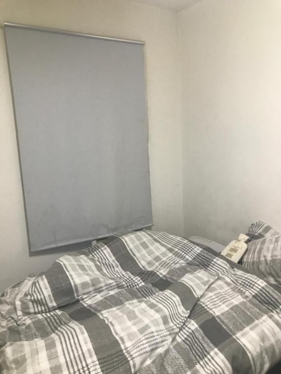 a bed with a plaid blanket in a room at Luxx apartment in Erith