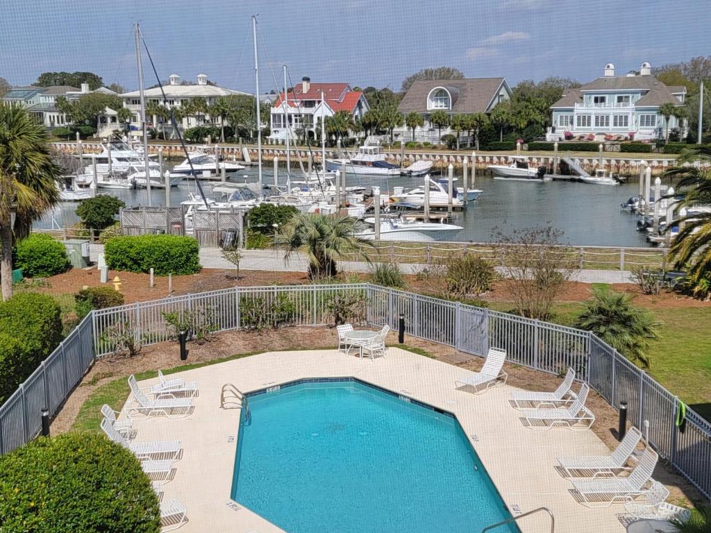 a swimming pool with lounge chairs and a marina at The Moorings Condo - Wild Dunes Resort - Isle of Palms Marina in Isle of Palms