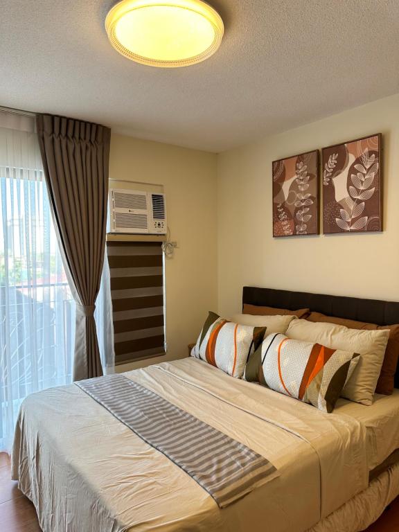 Un dormitorio con una cama grande y una ventana en Resort-inspired Condo with Queen-size bed & 50-inch Smart TV, en Cebú