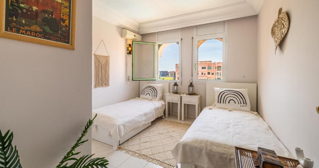 two beds in a room with a window at Charming 2-Bed Oasis Pool View in Marrakech