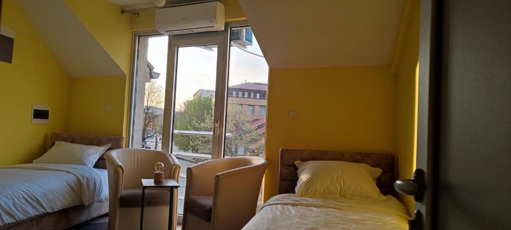 1 Schlafzimmer mit 2 Betten und einem großen Fenster in der Unterkunft Apartmani Ad fines in Kuršumlija