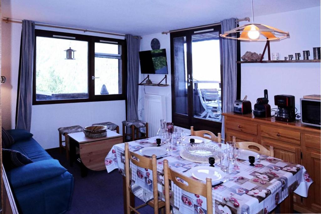 a dining room with a table and a blue couch at Résidence Le Meale - 3 Pièces pour 6 Personnes 241 in Les Orres